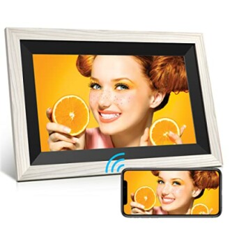 Digital photo frame displaying a smiling person holding orange slices, with a smartphone showing the same image.